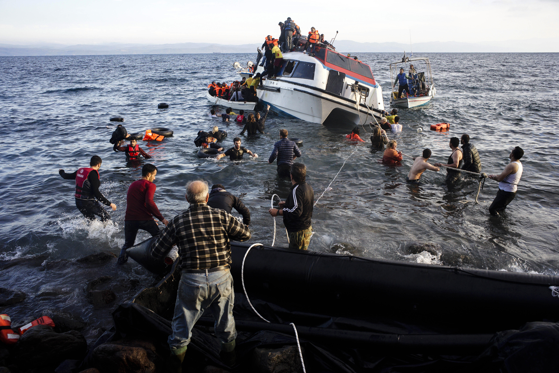 Volunteers and local residents help refugees and migrants disembark from a small vessel after their arrival in Skala Sykaminias on the northeastern Greek island of Lesbos on Friday, Oct. 30, 2015. Greek authorities say a number of people have died near other islands after two boats carrying migrants and refugees from Turkey to Greece sank overnight, in the latest deadly incident in the eastern Aegean Sea. (AP Photo/Kostis Ntantamis)